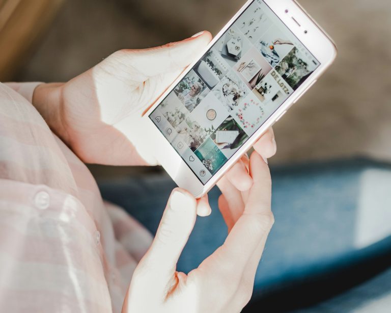 Person holding a smartphone displaying various images on the screen.