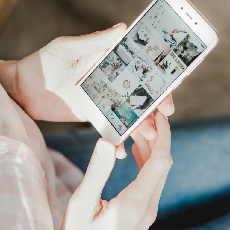 Person holding a smartphone displaying a grid of images and photos.